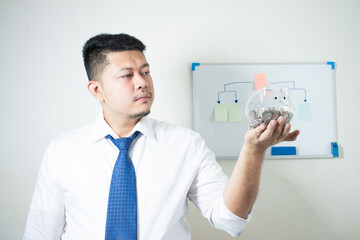 Portrait of happy successful Asian businessman holding piggy bank in hand, future investment concept