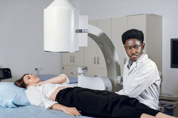 Young high-skilled focused black man doctor in white coat, providing lithotripsy procedure for his...