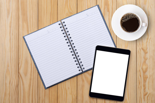 Mockup image of blank white notebook, digital tablet and cup of coffee isolated on wood board background. Top view. Flat lay.