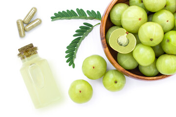 Indian gooseberry or Amla fruit with green leaf, bottle of essential amla oil extract and herbal medicine capsules pill isolated on white background.