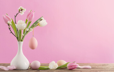 Obraz na płótnie Canvas Easter eggs and tulips in vase on pink background