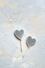Valentine concept, silver shining heart-shaped candles with glitter on grey texture