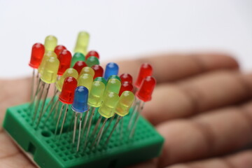 Group of colorful LED bulbs pinned to breadboard and held in hand isolated on white background