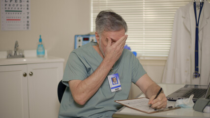 weary doctor filling out paperwork