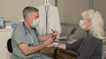 Obraz premium doctor checking the blood pressure of a mature patient