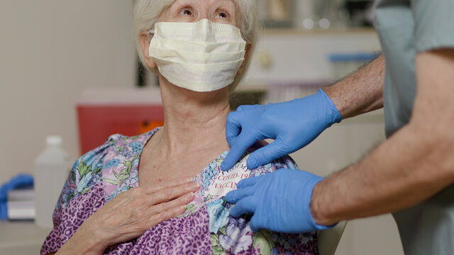 An Elderly Nursing Home Resident Gets A Sticker To Show She Has Gotten Vaccinated.