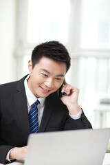 Portrait of businessman sitting at desk and using cell phone