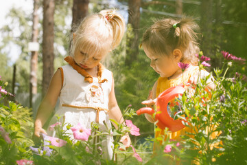Two little girls sisters watering flowers