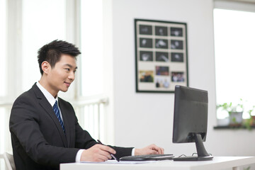 Portrait of businessman sitting at desk,looking at computer