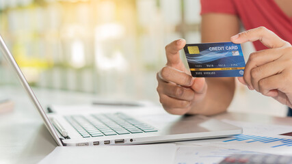 Girl holding mockup credit card and using laptop to shop internet at home online shopping concept