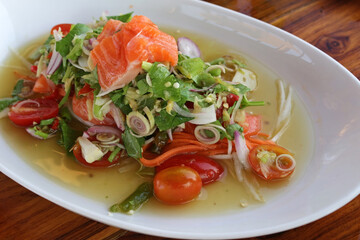 Asian spicy raw salmon salad with herbs and vegetables.
