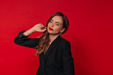 Incredible happy woman with red lips posing with closed eyes over isolated red background and preparing for celebrating Valentine's day