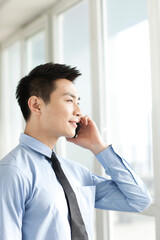 Fototapeta na wymiar Portrait of young businessman talking on cell phone in office