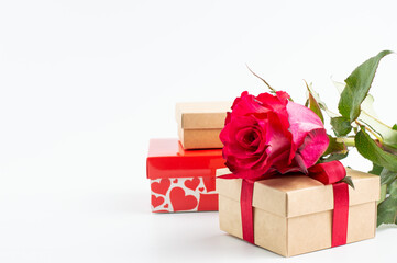 A red rose with gift boxes is placed on a white background with space for writing text.