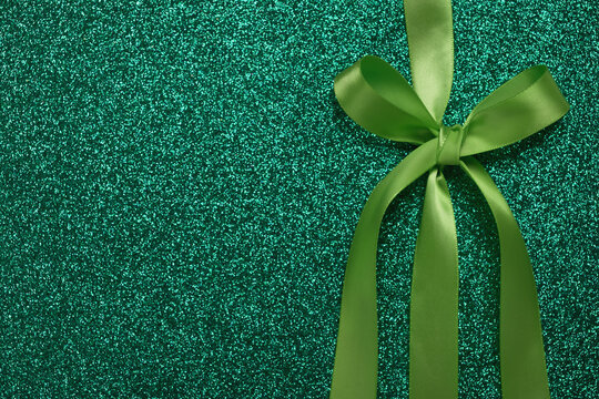 Green gift shiny card or texture gift box with ribbon bow. St Patricks Day concept, birthday, christmas background. Top view, flat lay, copy space, template for design
