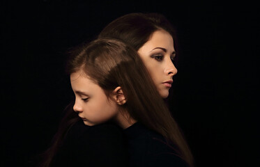 Sad serious thinking daughter hugging her unhappy mother with pensive face on black background in...