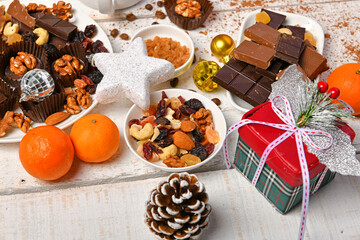 sweet food top view background for merry christmas or new year holiday decoration - chocolate candies, tangerines, cookies on white wood