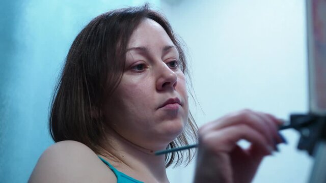 the artist draws a brush on a canvas standing on a tripod. home studio of fine arts. view of the girl's face from the bottom.