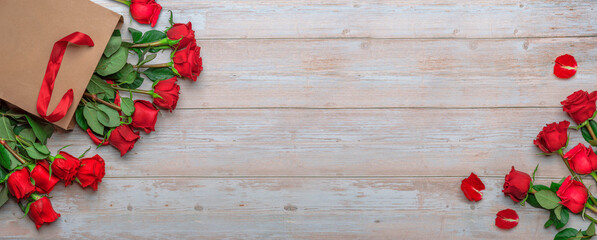 Red roses in craft shopping bag, a wooden surface. Banner delivery flowers for Valentine's Day 14...