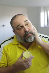 Man is using wax from beard grooming kit for fixing his beard.