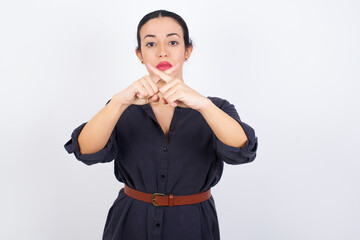young beautiful Arab woman wearing gray dress against white studio wall has rejection angry...