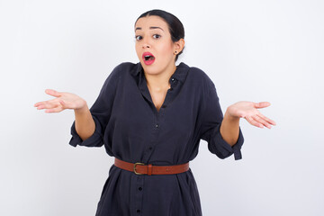 So what? Portrait of arrogant young beautiful Arab woman wearing gray dress against white studio...