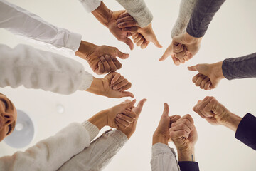 Group of people giving thumbs-up all together. Team celebrating teamwork and success, approving of...