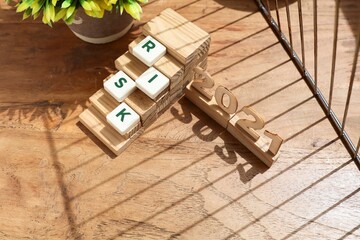 Block letters on risk on the stacked wooden sticks and number 2021 at the side  on the wooden table 