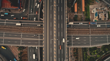 Top down cross traffic highway with cars, trucks aerial. Urban transportation at bridge road at metropolis city of Manila, Philippines, Asia. Cinematic cityscape of downtown freeway drone shot