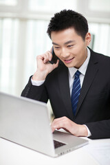 Portrait of businessman sitting at desk and using cell phone
