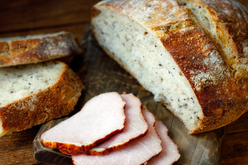 Healthy breakfast. Fresh crunchy homemade bread and ham lie on the cutting board. Homemade cakes with cereals. Photo in a rustic style.
