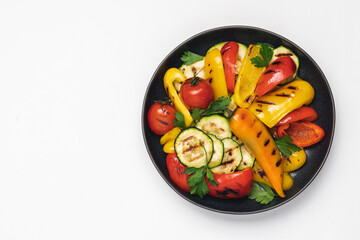 Variety of grilled vegetables in bowl on white background. Zucchini, bell peppers, hot peppers, tomatoes and green parsley