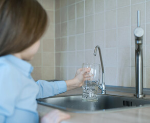Child is pouring water from filter tap. Kitchen faucet. Quenches thirst. Filter system or osmosis,...