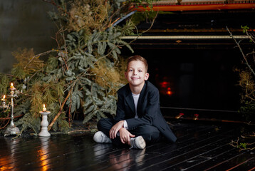 Little smiling boy sit on wooden floor with christmas candlestick.