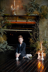 Little boy sit on wooden floor with christmas candlestick. Cozy living room.