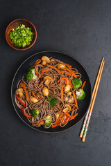 Vegan Stir fry with vegetables and mushrooms  in black bowl. Close up view. Black slate background
