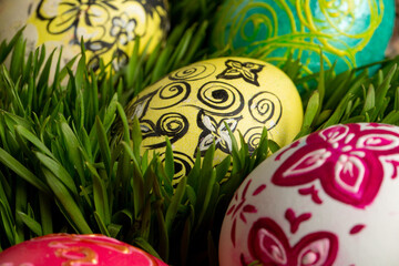 Many colored eggs with ornaments  on green grass