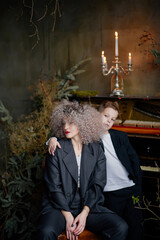 Portrait of a mother with son wearing stylish clothes on the background piano.
