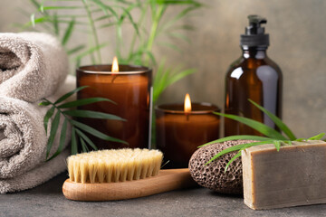 Spa composition with candles, towels, massage brush, volcanic pumice stone, care cream in dark...