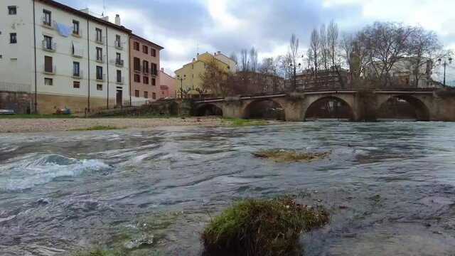 Riverbed with running waters and city and bridge in a time lapse view. Ega river in Estella city, Navarre, Spain, Europe.
