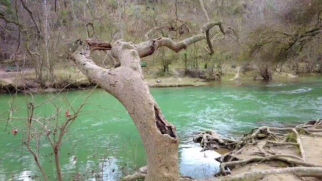 Riverbed with running waters and banks with trees in winter in a time lapse view. Ega river close to Estella city, Navarre, Spain. Europe.