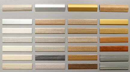 Wooden skirting board samples with different colors for different types of floor. Gray background.