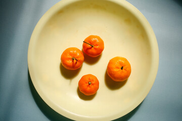 Flat lay small ripe tangerines on yellow plate