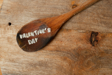 wooden spoon with letter paste with the word valentine's day on a wooden table