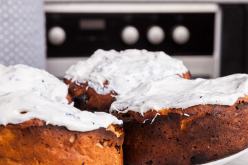  four Easter cakes on a plate on a table with white icing cooked in the home kitchen prepared for decoration with colored confetti.