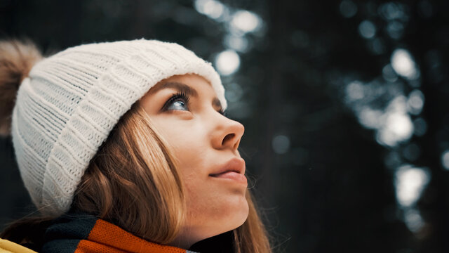 Girl with a white hat in the forest with a backpack in winter. Side view. Close up