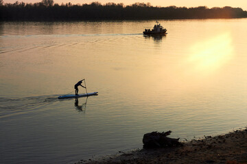 Top view of silhouette of man rowing on stand up paddle boards (SUP) on the river at sunset