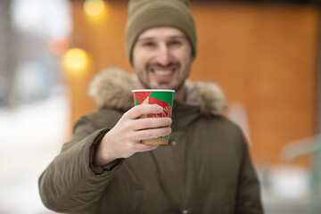 Photo of a happy excited young man standing posing outdoors winter concept drinking coffee.