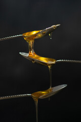 Spoons with raw honey bee on dark background, healthy nutrition concept