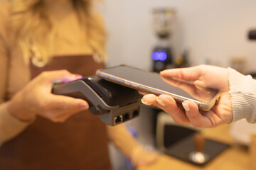 Close Up of a Woman Hand Holding a Smartphone with an NFC Payment Technology Used for Paying for Take Away Coffee in a Cafe.